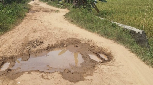 Salah satu titik jalan rusak parah penghubung antar Desa Silau raja dan Desa Taman Sari, Kamis (24/7/2025) (04/iKoneksi.com)